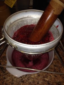 Straining the raspberry and rhubarb pulp and seeds from the raspberry shrub