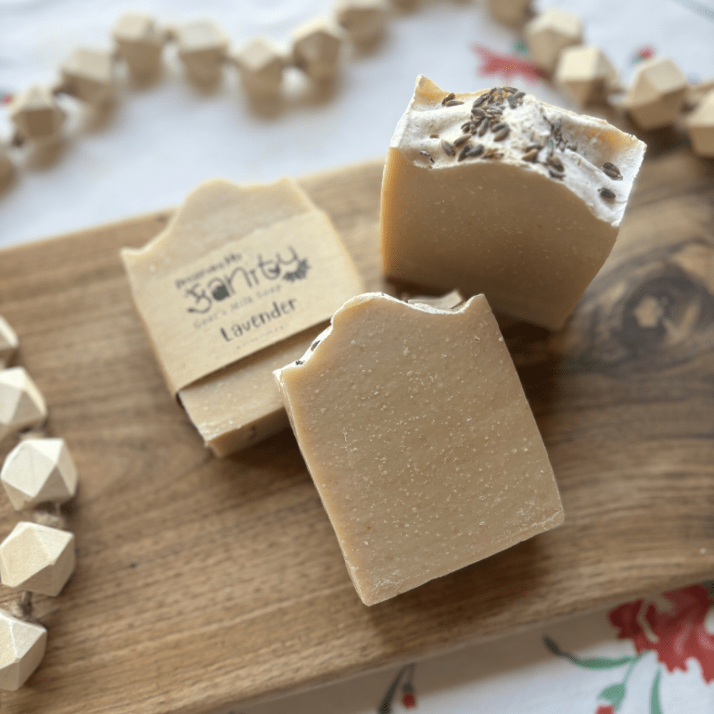 Flatlay photo of three bars of lavender essential oil soap, one showing the top with dried lavender flowers