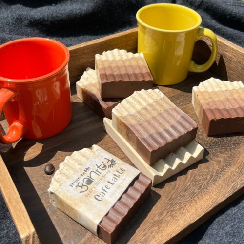 Exterior flatlay of cafe latte soap pictured with coffee mugs on a sunny day