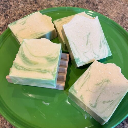 Interior flatlay photo of pretty coconut lime verbena soap on a bright green Fiesta cake plate with a made in the USA wooden soap dish