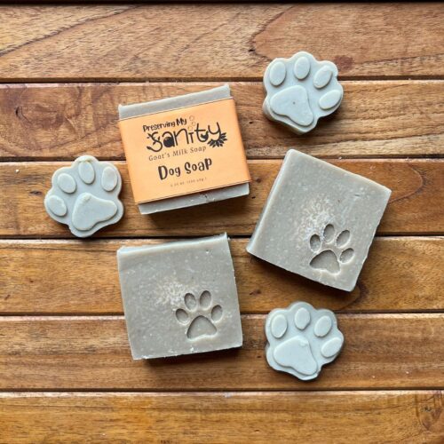 Plain interior flatlay of some bars of imprinted dog paw soap and small dog paw samples with a stained wood background
