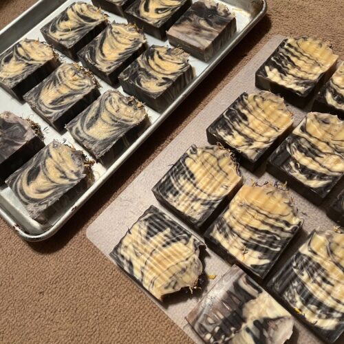 Flatlay of bars of lavender orange soap on trays after cutting before going to the curing rack