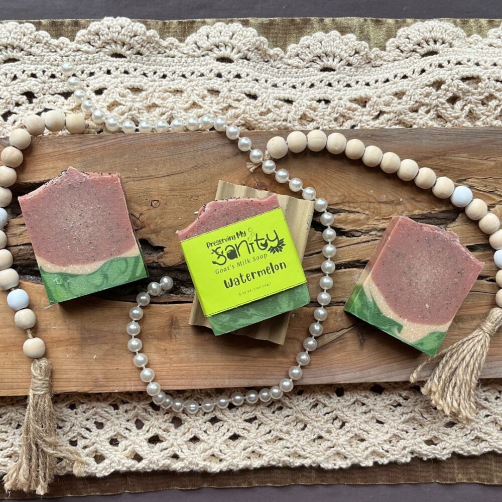 Pretty interior flatlay of watermelon soap featuring a backdrop of rustic wood, wooden beads, pearls, and crochet