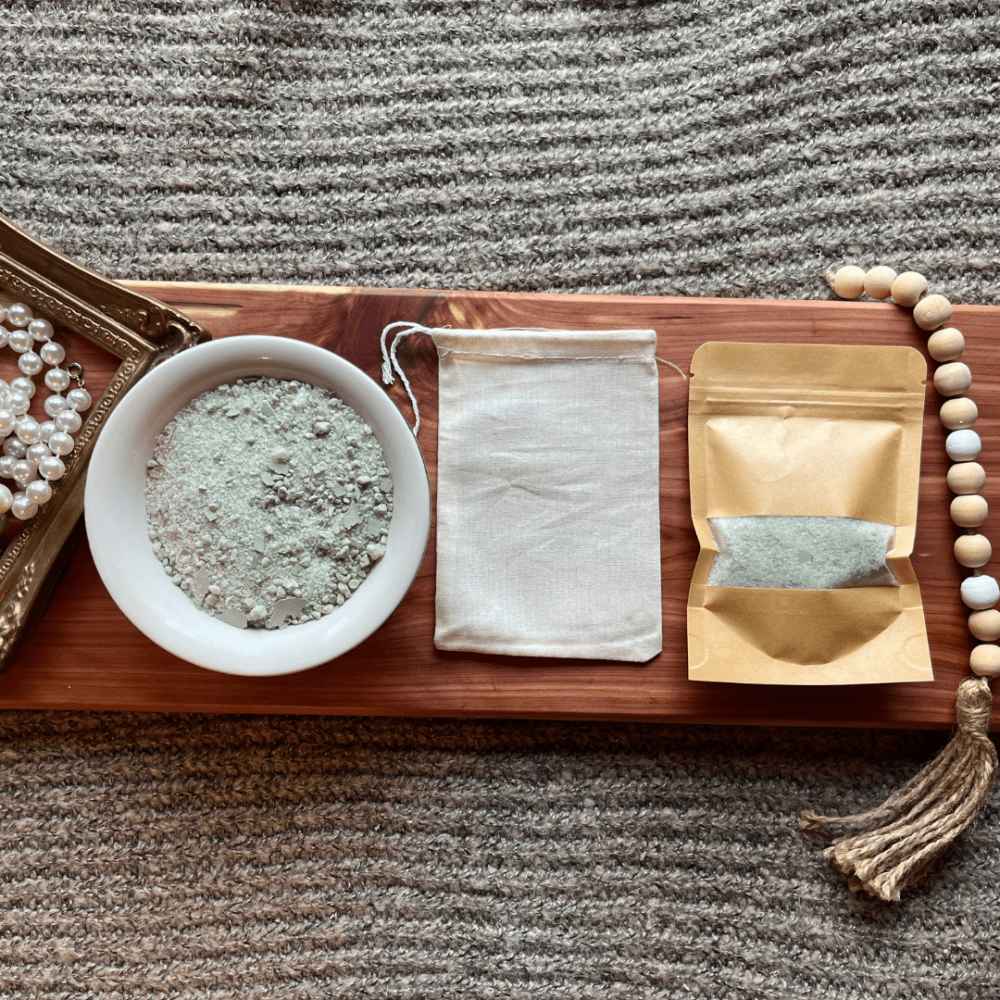 Flatlay photo showing a bowl of eucalyptus bath salt, with a package of bath salt and a reusable cheesecloth bag.