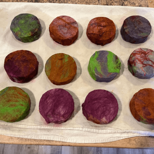 Process photo of a dozen bars of felted Nag Champa soap drying on a towel