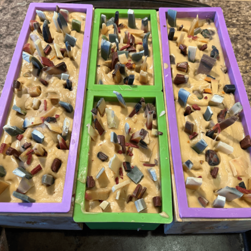 Process photo of three batches of holiday confetti goat's milk soap in the molds just after being poured