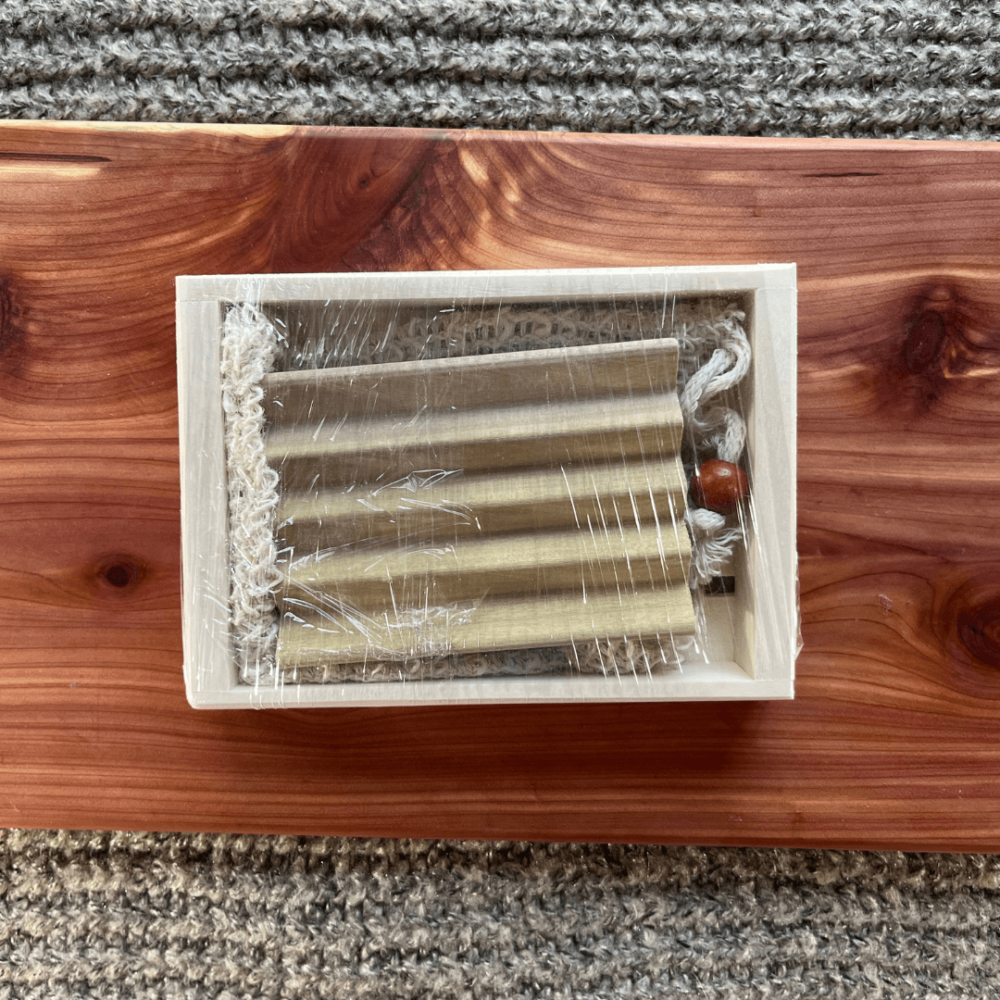 Flatlay photo of a "just add soap" gift set that includes a reclaimed wood try, a sisal soap bag, and a natural wood soap dish
