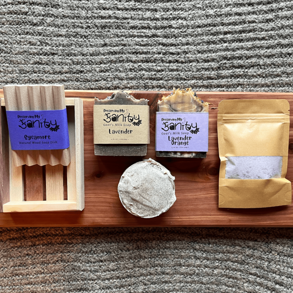 Flatlay photo of the lavender lovers bundle that includes a lavender bath salt, lavender soap, lavender luffa soap, lavender orange soap, a wood soap dish, and a reclaimed wood gift tray