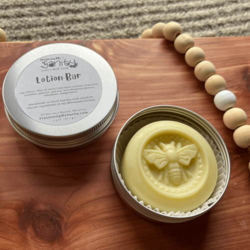Alternate view of handmade lotion bar made in a bee mold in a flatlay photo on a cedar board