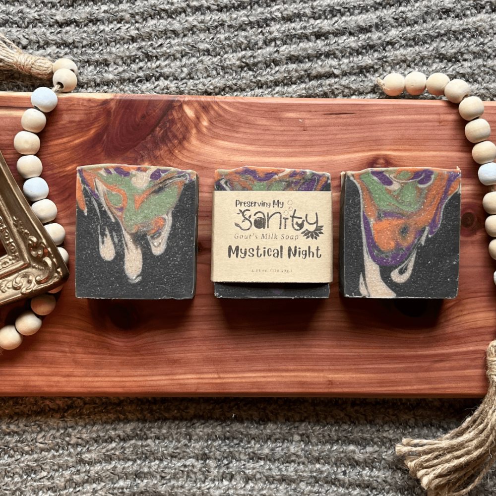 Flatlay photo of three bars of Mystical Night goat's milk soap on a cedar bath board