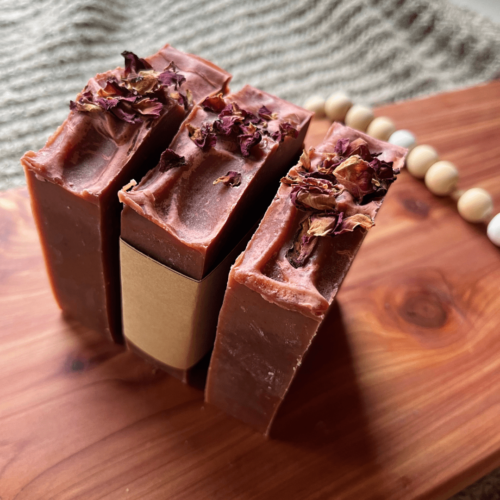 Side and top view of three bars of Rose Garden soap with rose petals on top of goat's milk soap bars