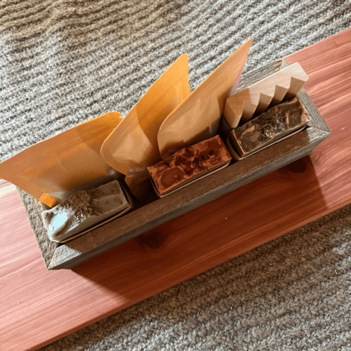 Alternate view of the soap and salt bundle that includes a reclaimed wood trough, three bags of bath salt, three bars of handcrafted goat's milk soap, and a wood soap dish