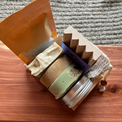 Alternate overhead view of the spa day bundle that includes oatmeal chamomile bath salt, coconut lime verbena bar soap, litsea and orange shaving soap, beachy luffa soap, lotion bar, wood soap dish, sisal soap saver bag, and reclaimed wood gift tray