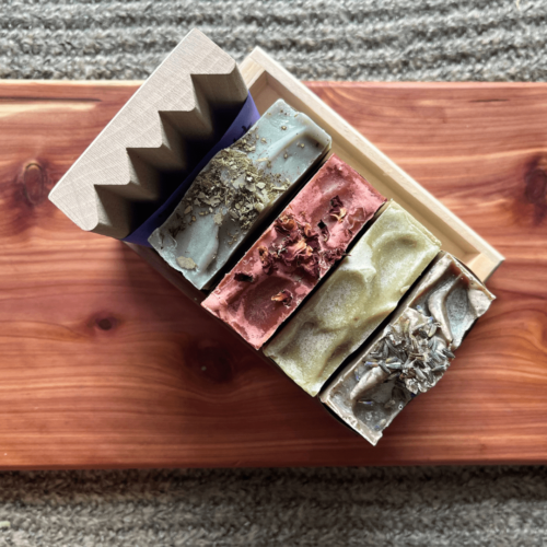 Upper view photo of four bars of essential oil soap and a wooden soap dish inside the reclaimed wood gift tray for holiday gift giving
