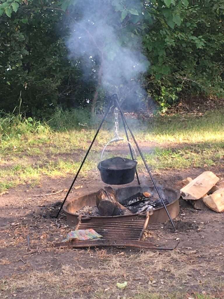Photo of a cast iron dutch oven on a tripod over a campfire