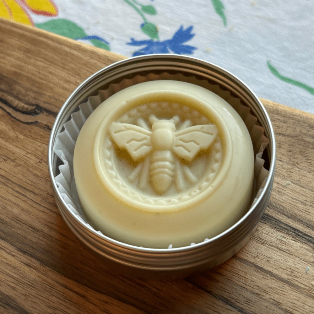 Flatlay photo of a citronella and herb lotion bar in a reusable aluminum tin