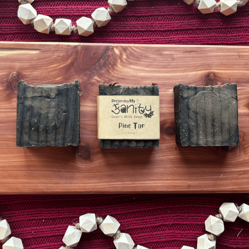 Flatlay of three bars of pine tar soap sitting on a cedar bath board