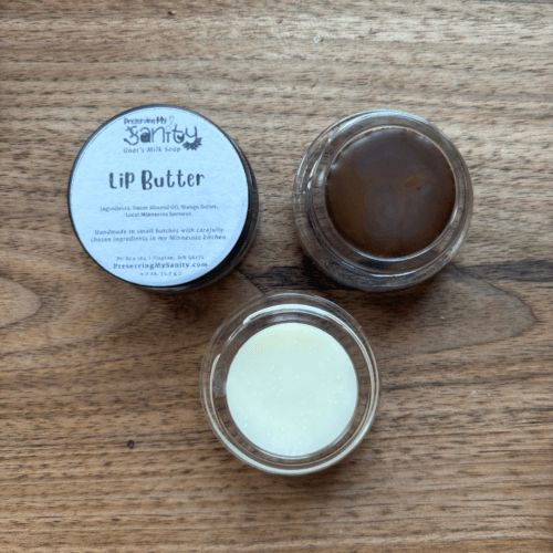Flatlay photo of two small jars of lip butter - one untinted and one brown/plum.