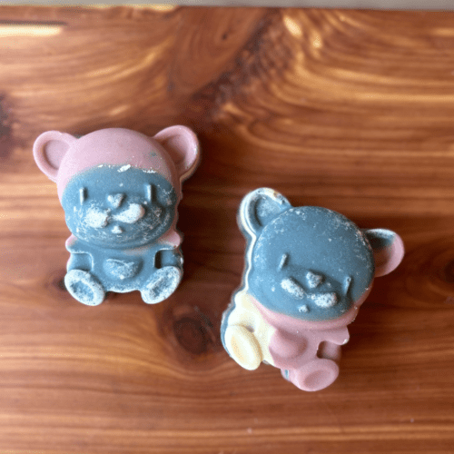 Photo of two bars of bear-shaped goat milk soap displayed to show colors and faces of animals