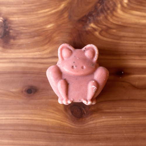 Photo of one bar of frog-shaped goat milk soap displayed to show color and face of animal