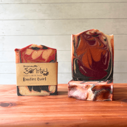 Photo of three bars of bonfire swirl goat milk soap displayed to show design, top, and label