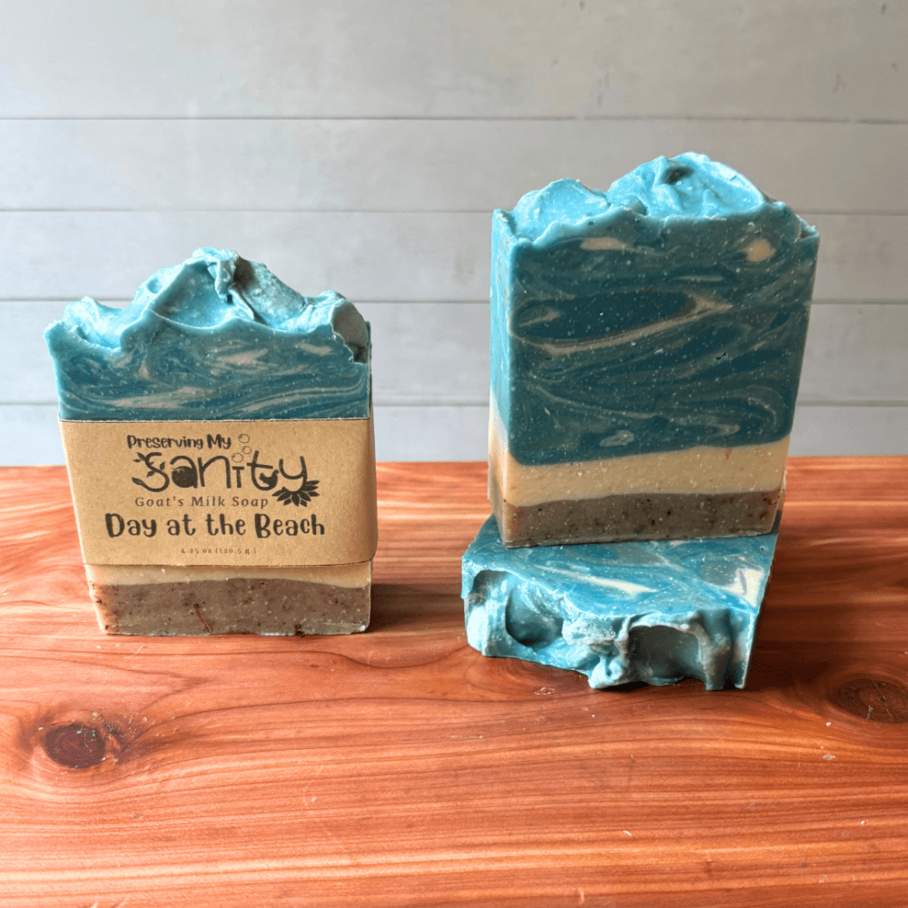 Photo of three bars of day at the beach goat milk soap displayed to show design, top, and label