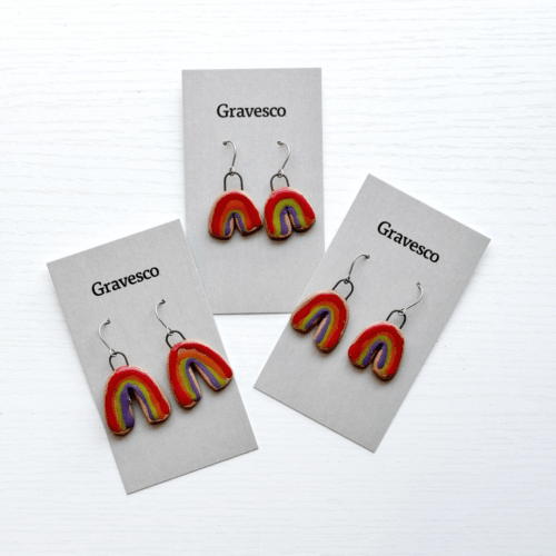 Flatlay photo showing three pairs of ceramic rainbow earrings with a white background