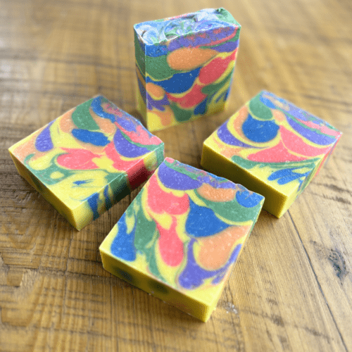 Flatlay photo showing the top and one side of four bars of Sunburst goat milk soap, photo used in the April 2024 Soap Challenge Club entry