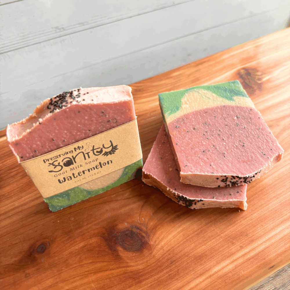 Threee half-size bars of Watermelon goat milk soap, pictured to show various angles and parts of this bestselling soap design that looks like a slice of everyone's favorite summer treat. Pictured on a cedar board with white panel background.
