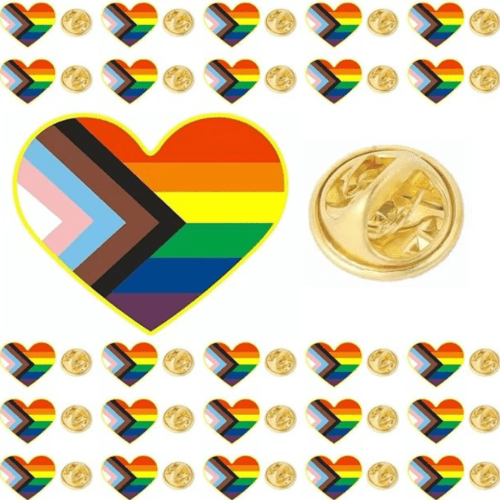 Flatlay photo showing a variety of rainbow pride lapel pins with a progress pride heart