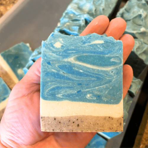 Process photo showing a bar of Day at the Beach goat milk soap in my hand just after cutting two batches of this handcrafted small batch soap made in Minnesota.