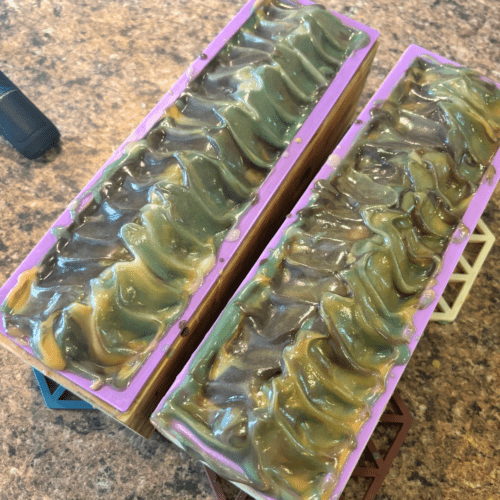 Process photo showing two loaves of freshly poured Minnesota Woods goat milk soap with textured tops.