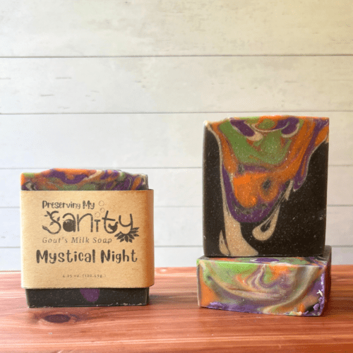 Display photo showcasing three bars of Mystical Night Halloween goat milk soap, handcrafted in small batches in Minnesota. These drop swirl bars feature black, white, purple, orange, and green and are scented with a dark and dreamy fragrance that's perfect for this fun holiday.