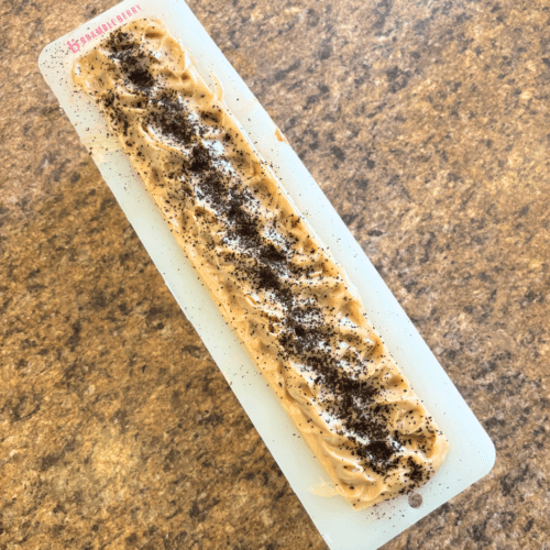 Overhead flatlay view of freshly poured pumpkin spice coffee goat milk soap poured in a silicon soap mold. Shown just after pouring the batter into the mold, two days prior to cutting into bars.