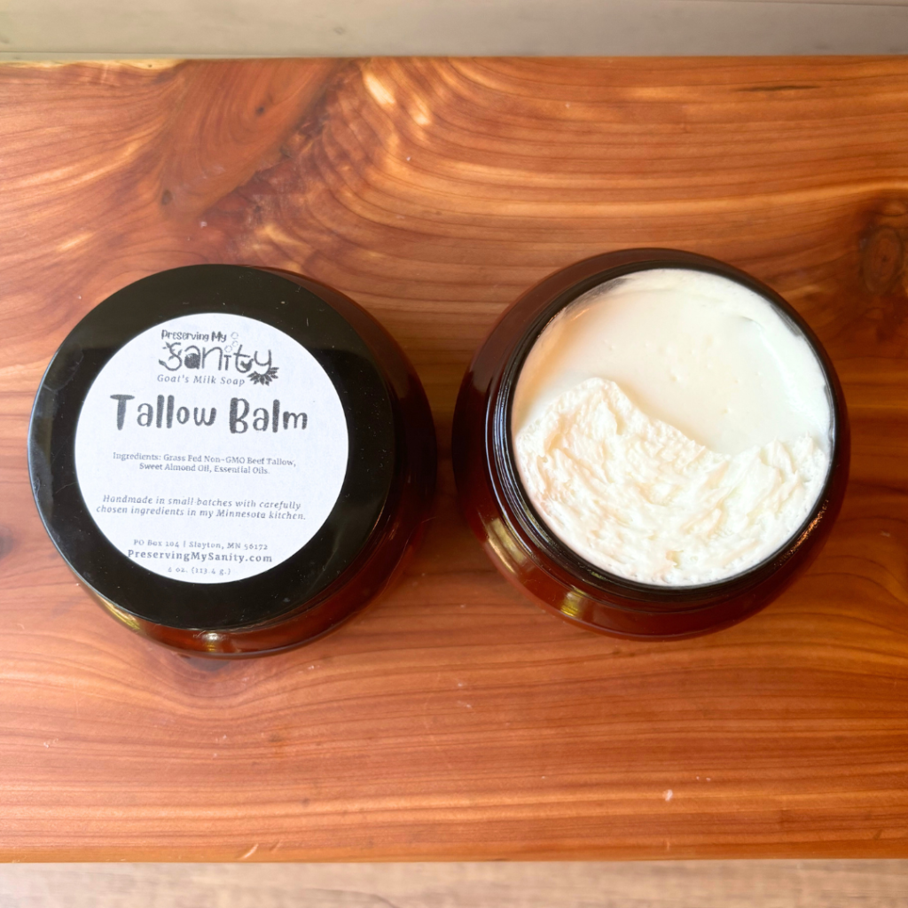 This photo is an overhead flatlay view of two jars of whipped tallow balm, one jar to show the label and the other to show the texture and consistency of the tallow balm.