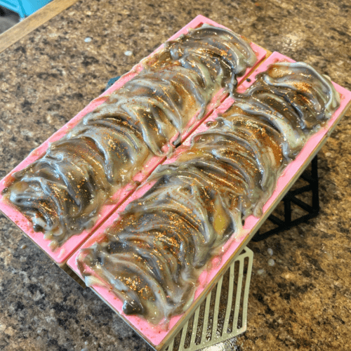 Process photo showcasing two loaves of small batch goat milk soap, these are toasted marshmallow as part of the fall collection. Photo was taken shortly after pouring the soap batter into the molds, texturing the tops, and sprinkling copper mica on top.