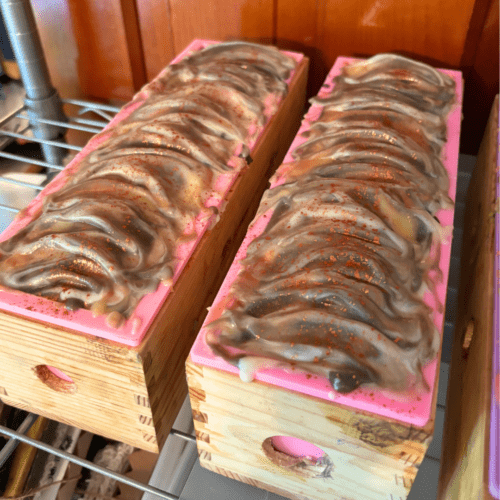 Alternate view of a process photo showcasing two loaves of small batch goat milk soap, these are toasted marshmallow as part of the fall collection. Photo was taken shortly after pouring the soap batter into the molds, texturing the tops, and sprinkling copper mica on top.