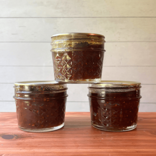 Front view photo of three small jars of tomato jam made with my homegrown tomatoes in my Minnesota garden.