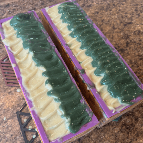 Process photo showing two full loaves of freshly poured Christmas Sweater goat milk soap with a textured top