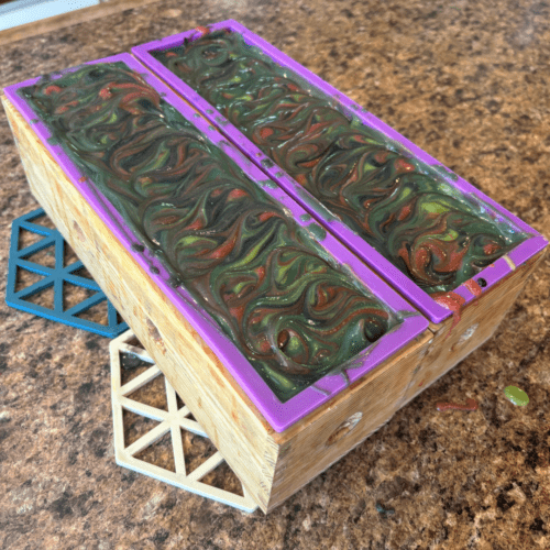 Process photo showing two loaves of freshly poured Forest Berries goat milk soap with textured tops.