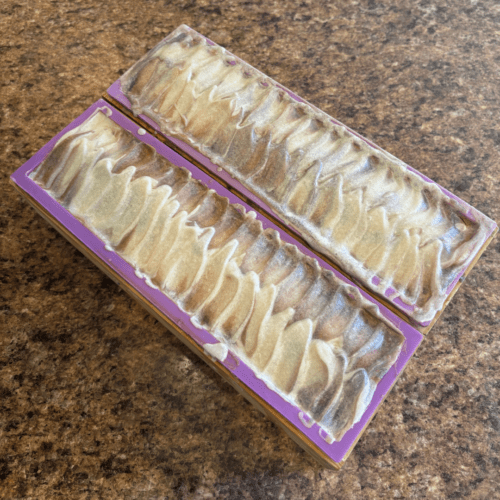 Process photo showing two loaves of freshly poured Forest Breeze goat milk soap with textured tops.