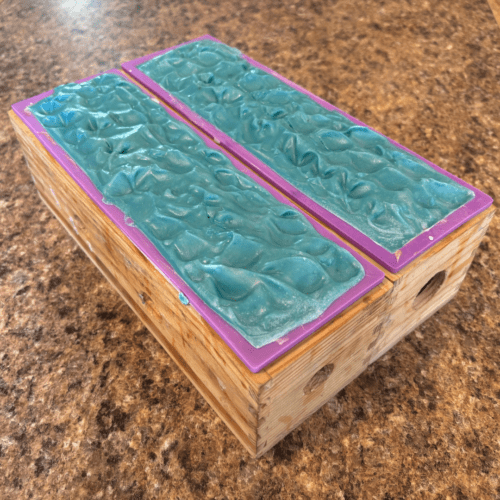 Process photo showing two loaves of freshly poured Freedom goat milk soap with textured tops.