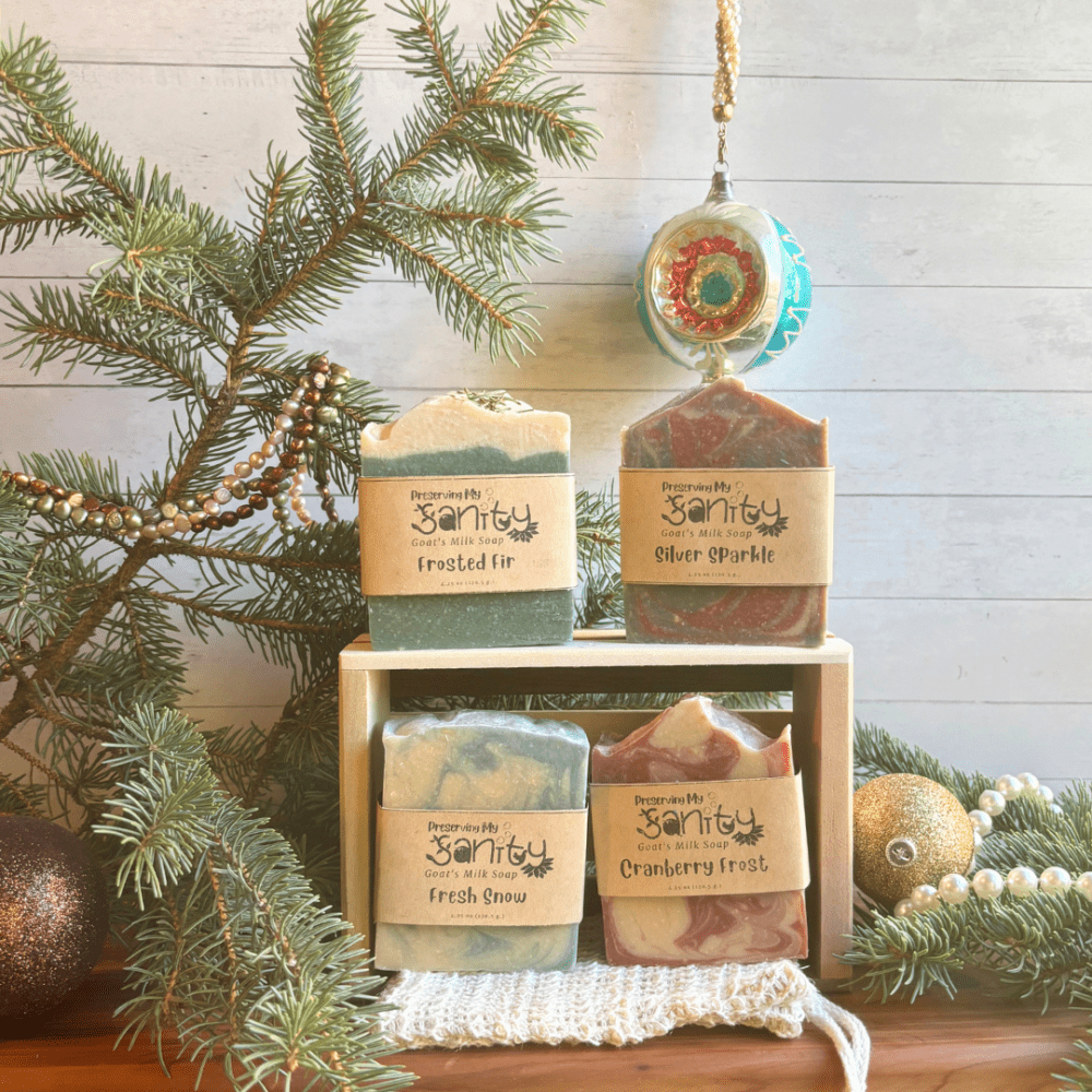 Display photo showcasing the items included in the holiday soap bundle - four full size bars of goat milk soap, a soap saver bag, and a reclaimed wood gift tray