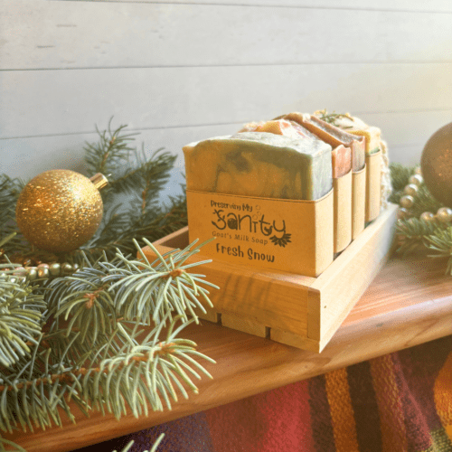 Front view of four bars of full size holiday soap pictured with a soap saver bag and reclaimed wood gift tray, included in the holiday soap bundle