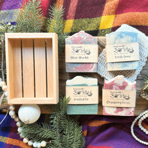 Overhead flatlay view of four bars of full size holiday soap pictured with a soap saver bag and reclaimed wood gift tray, included in the holiday soap bundle