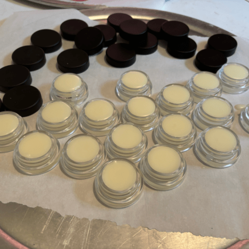 Process photo showing freshly poured jars of untinted lip butter made with local Minnesota beeswax