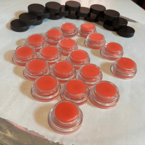 Process photo showing freshly poured jars of pink tinted lip butter made with local Minnesota beeswax