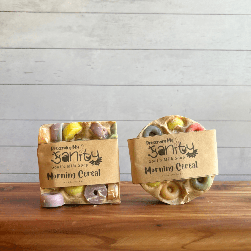 Display photo showing two sizes of Morning Cereal goat milk soap - a round bar and a square bar, with colorful loop cereal made of soap on top