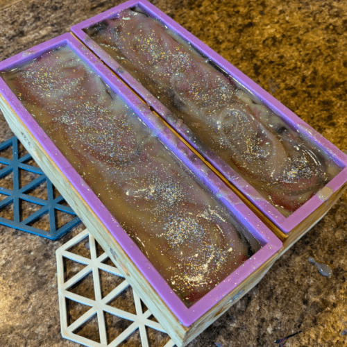 Process photo showing two full loaves of freshly poured Sugar Plum Fairy goat milk soap with biodegradable sprinkles on top