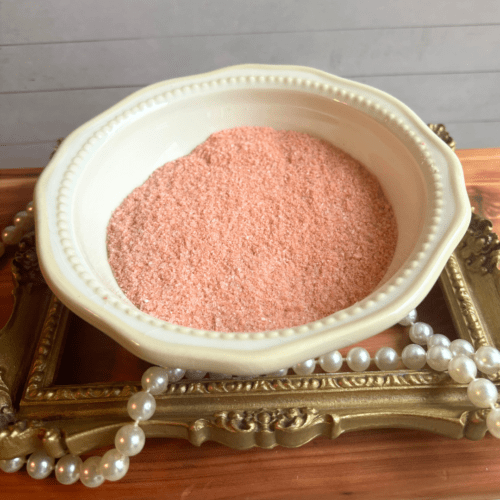 Small bowl of Classic Rose bath salt sitting on a gold frame with pearls